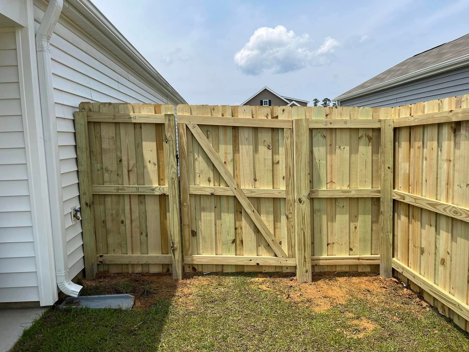 A wooden fence with a gate in the backyard of a house.