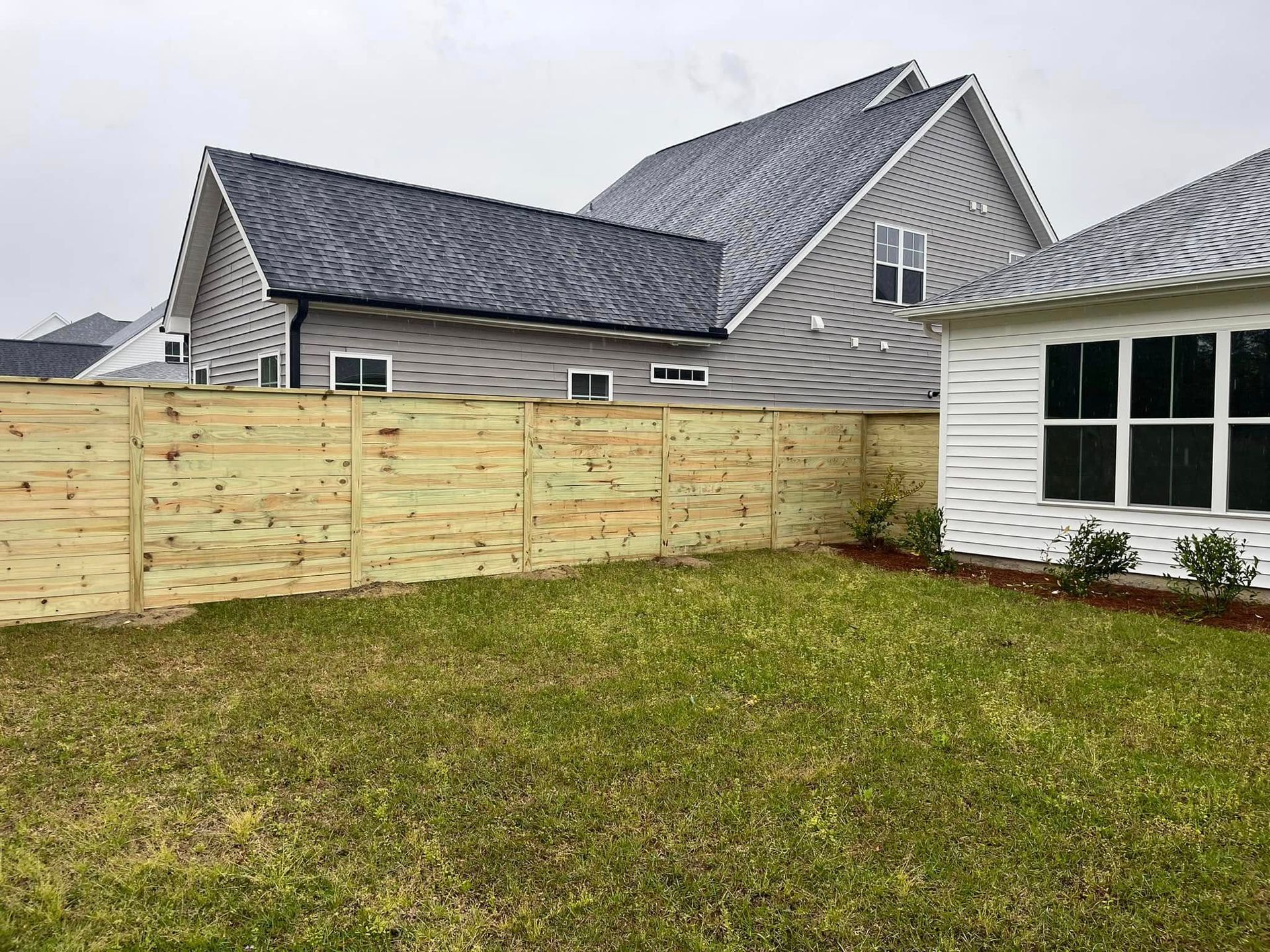 There is a wooden fence in the backyard of a house.