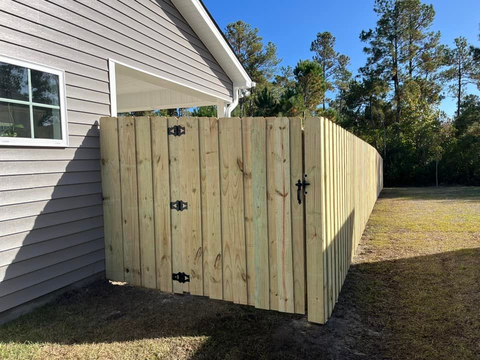 A wooden fence with a gate is in front of a house.