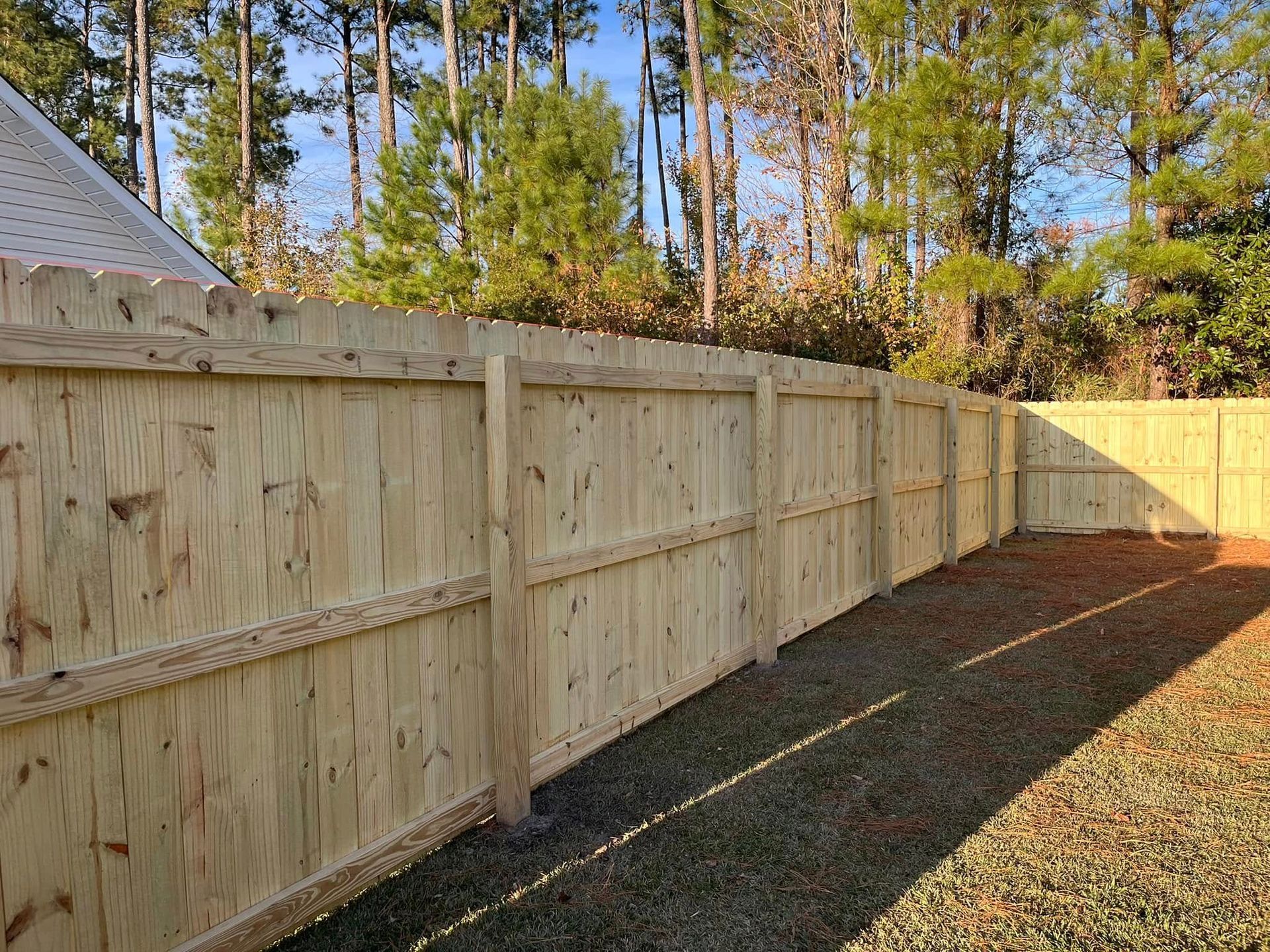 A wooden fence is in the backyard of a house.