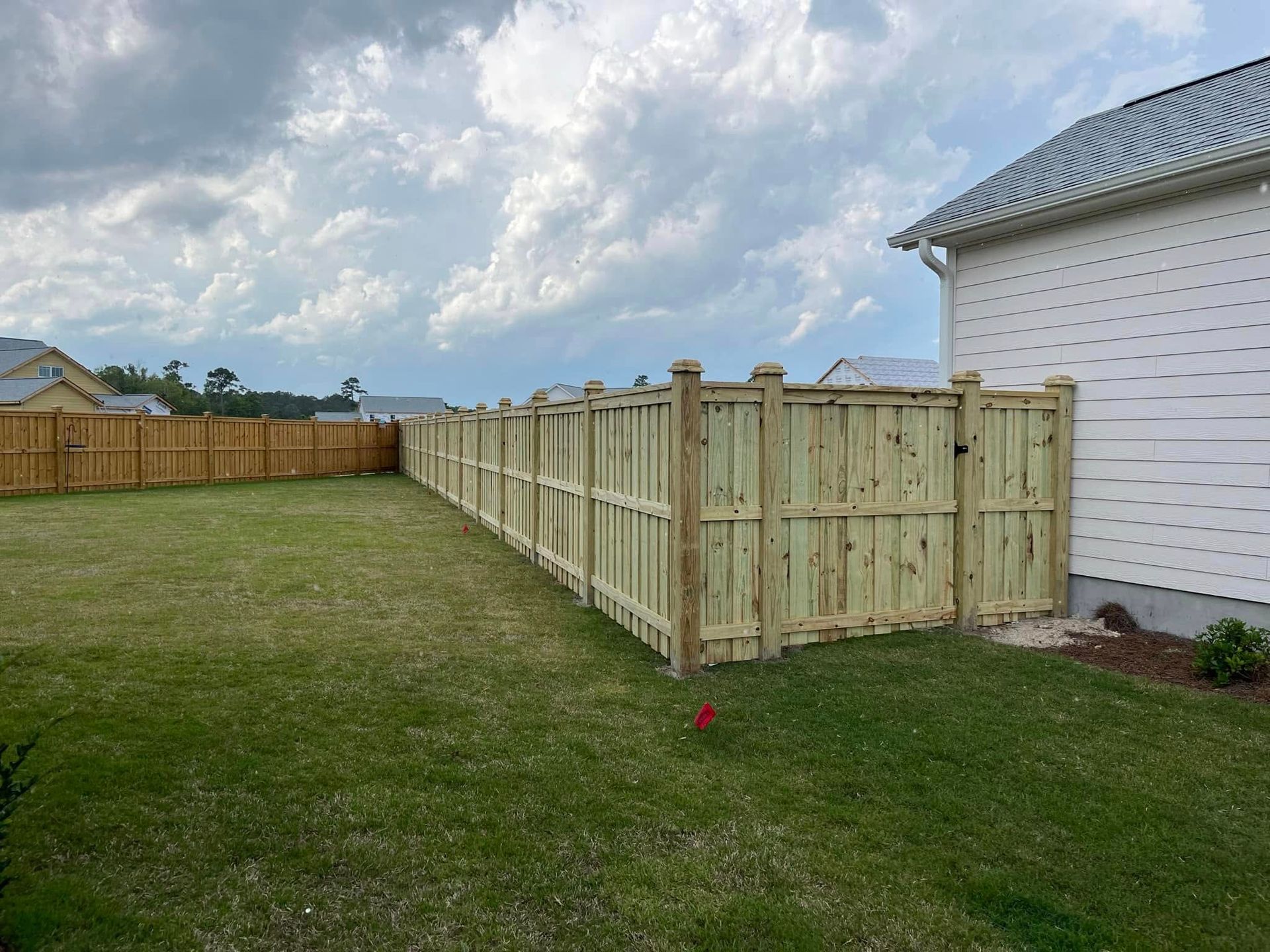 A wooden fence is in the backyard of a house.
