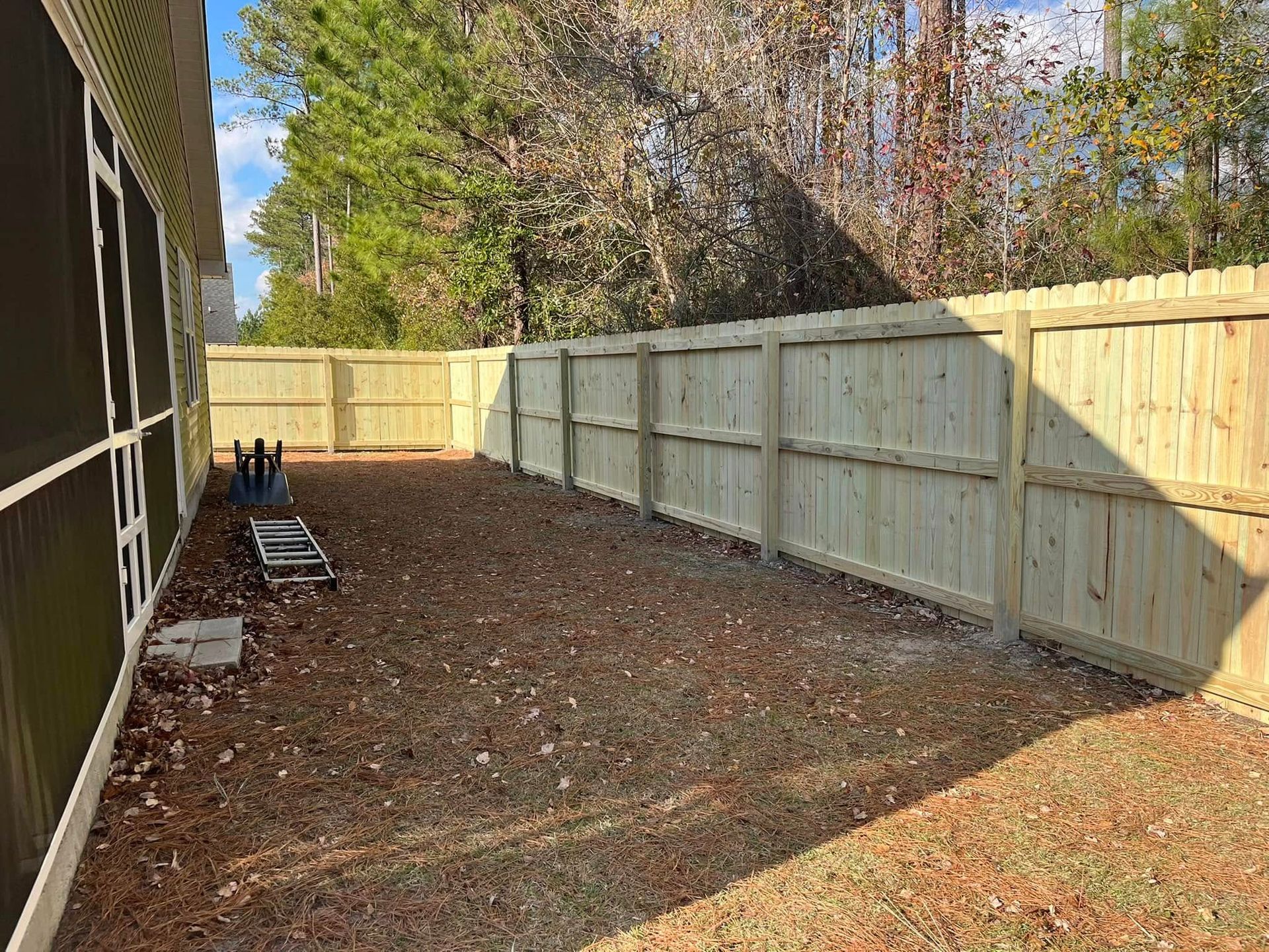 There is a wooden fence in the backyard of a house.