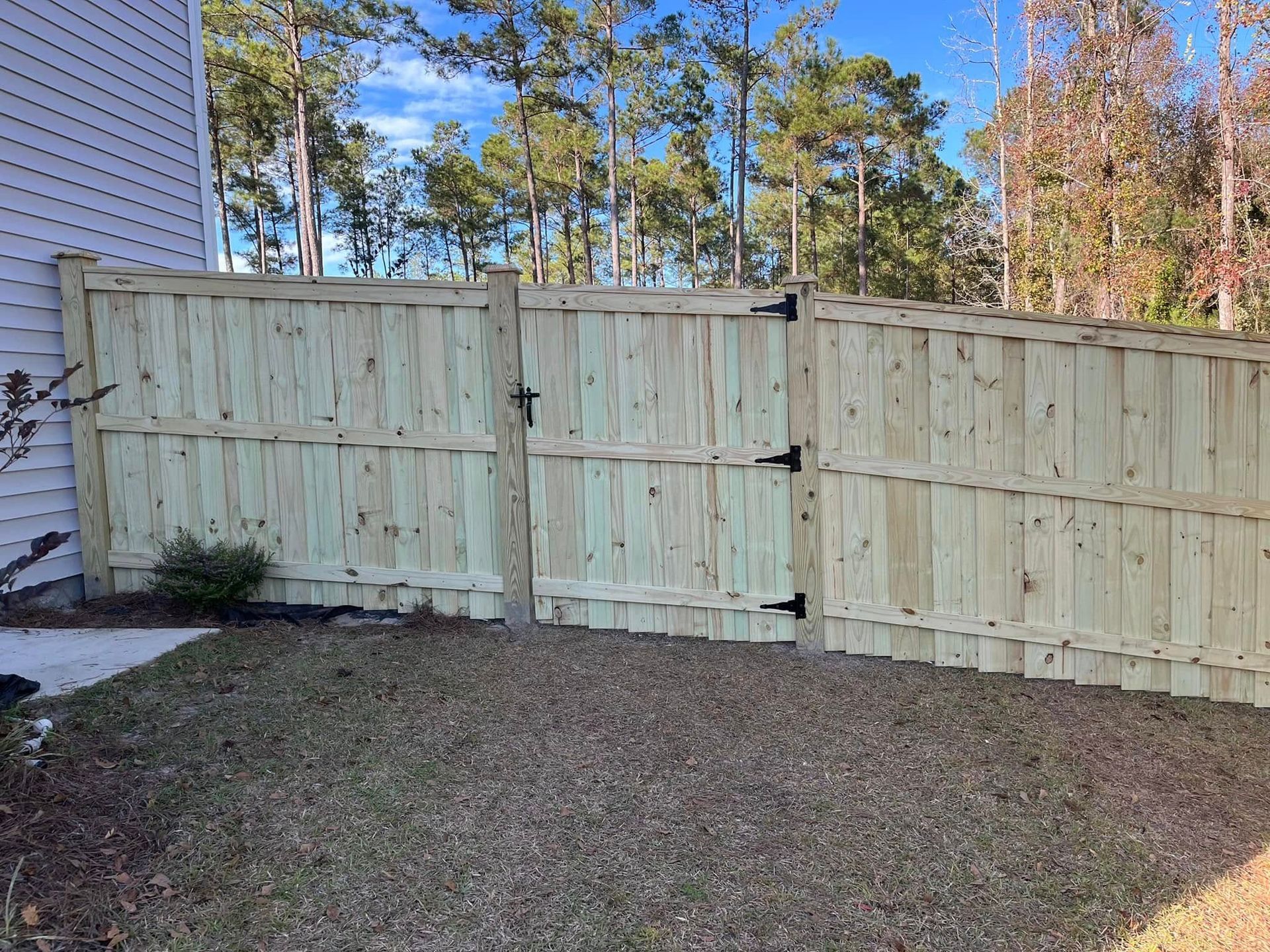 A wooden fence with a gate in the backyard of a house.
