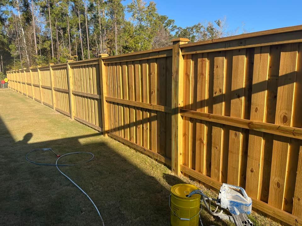A wooden fence is being painted in a backyard.