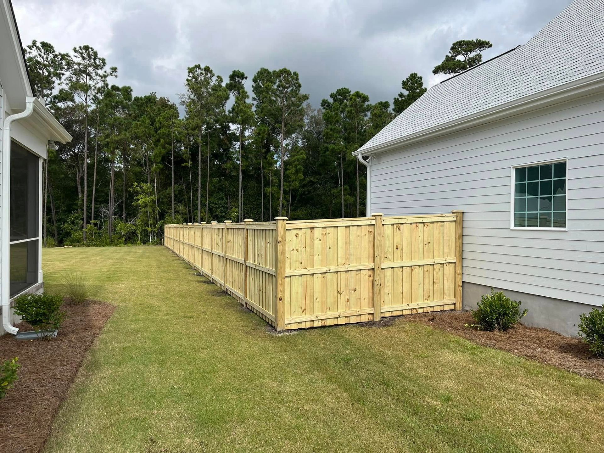 A wooden fence is in the backyard of a house.