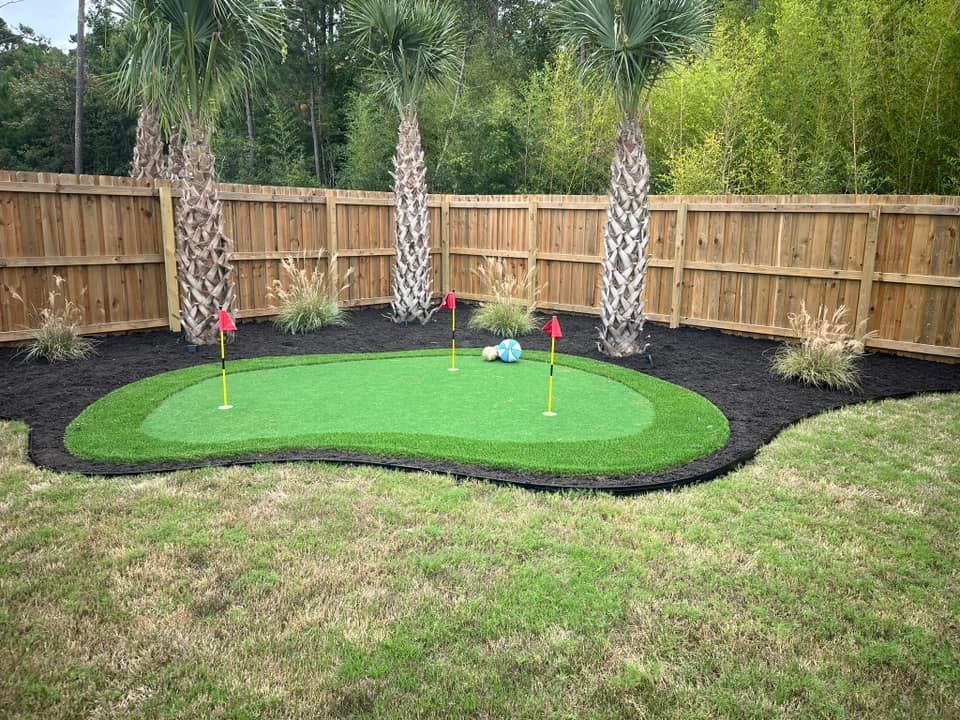 A backyard with a putting green and a wooden fence.