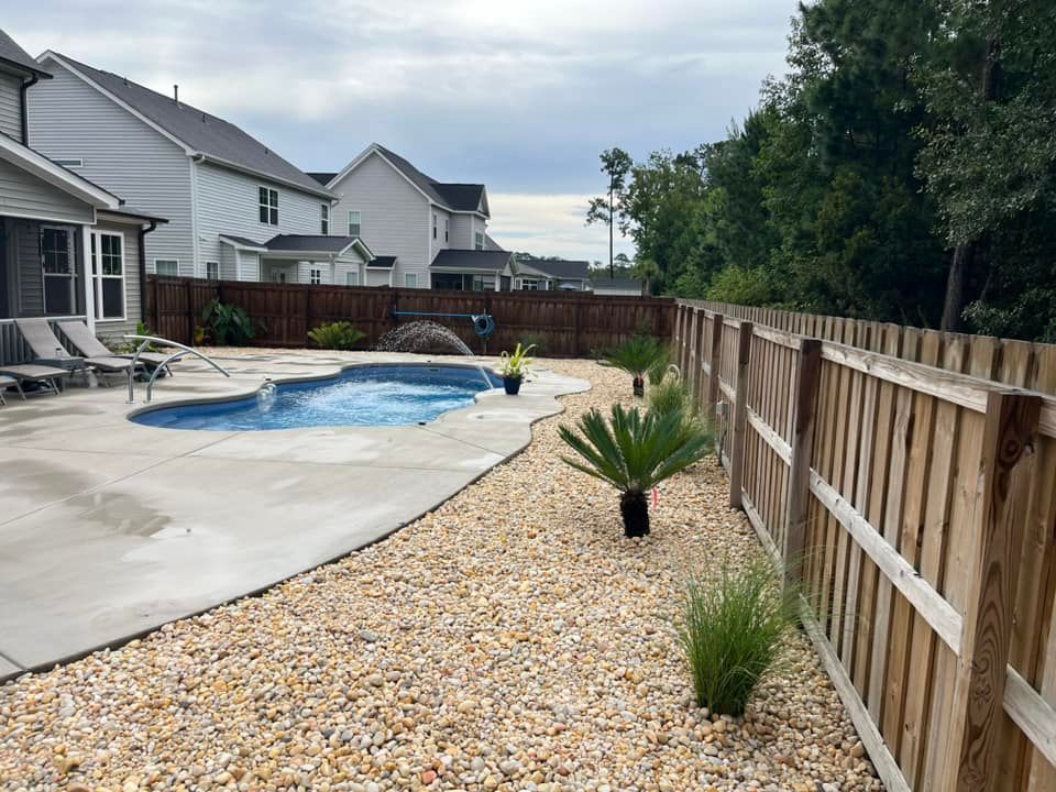 A wooden fence surrounds a swimming pool in a backyard.