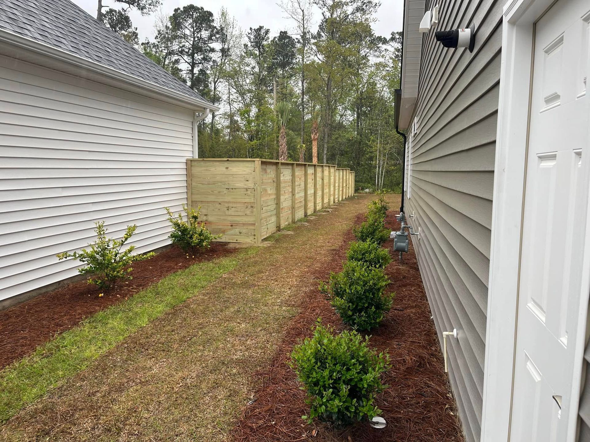 There is a wooden fence between two houses.