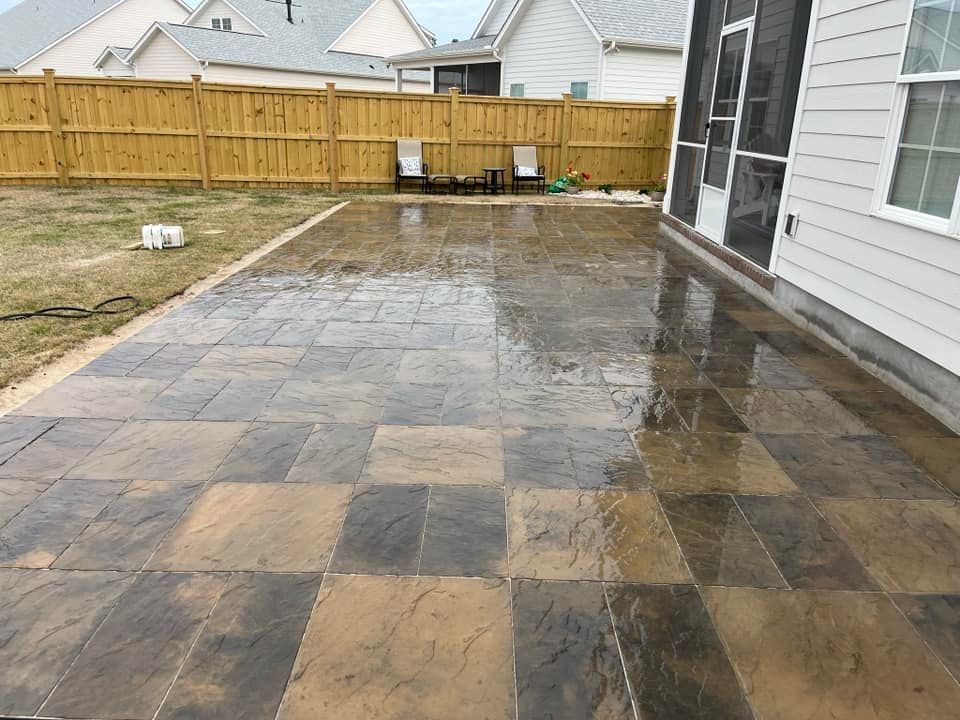A patio with a wooden fence and chairs in front of a house.
