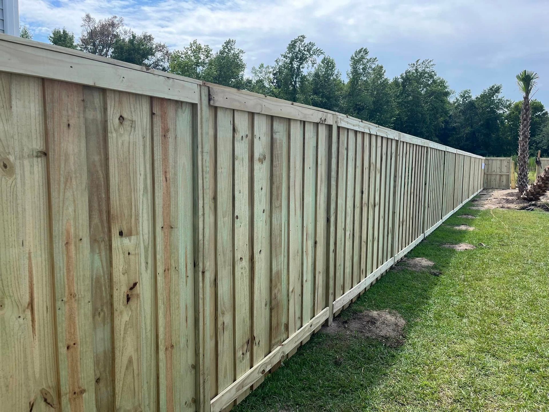 A wooden fence is sitting in the middle of a lush green field.