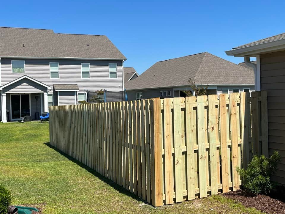 A wooden fence is in the backyard of a house.