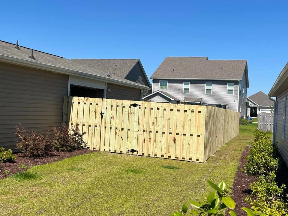 A wooden fence is in the backyard of a house.