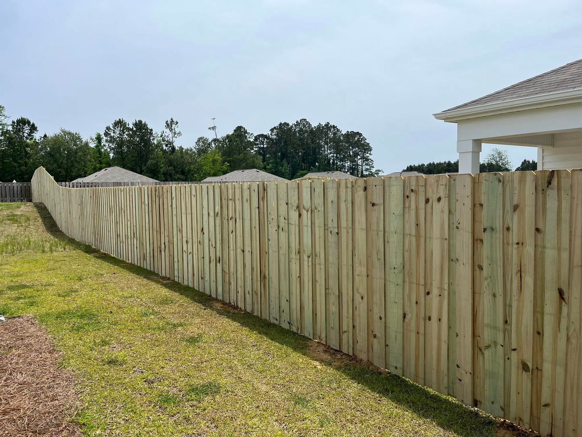 A wooden fence is in the backyard of a house.