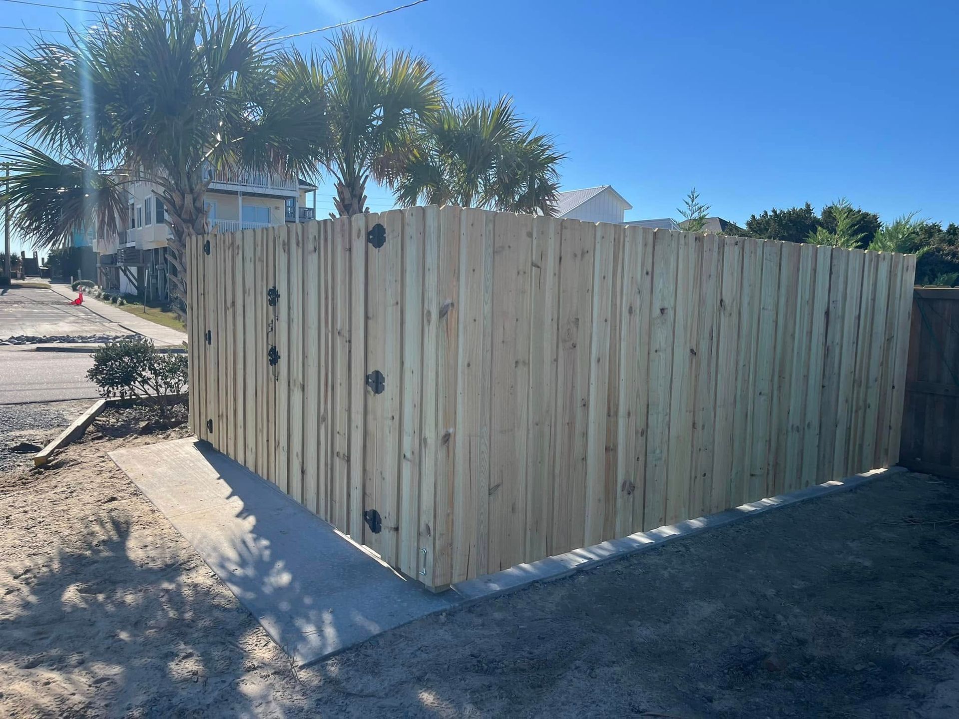 A wooden fence is sitting on the side of a road next to a sidewalk.