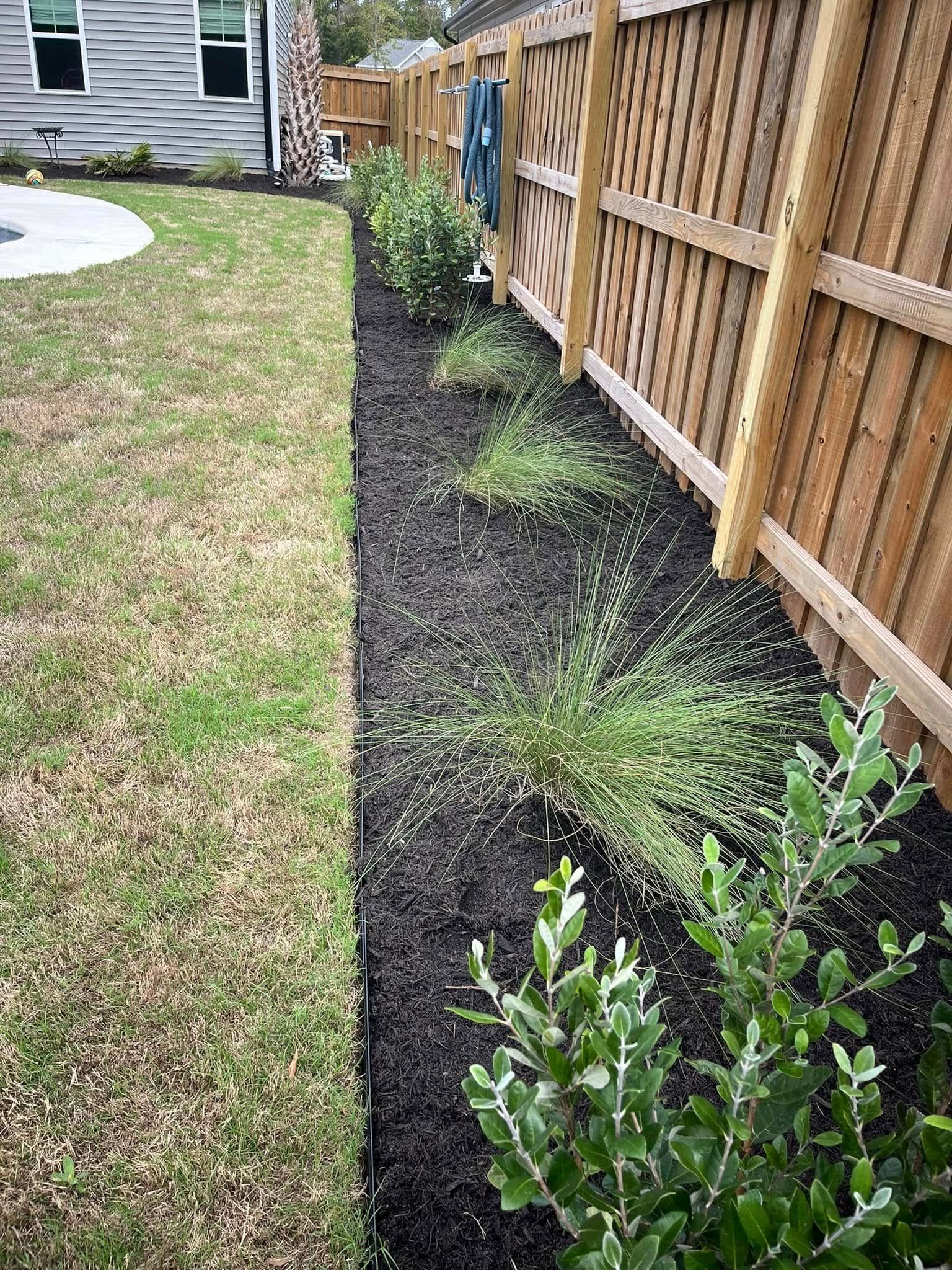 A wooden fence surrounds a lush green yard.