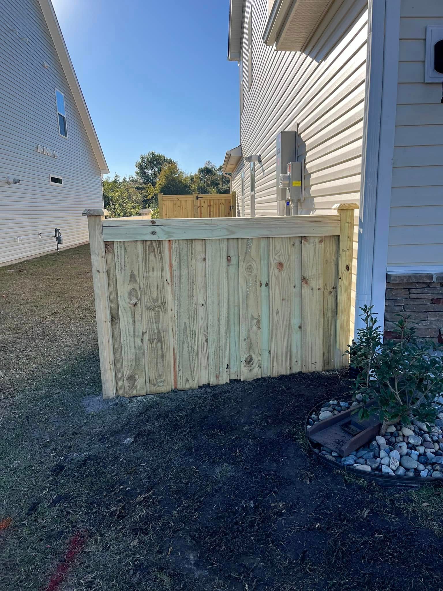 A wooden fence is sitting next to a white house.