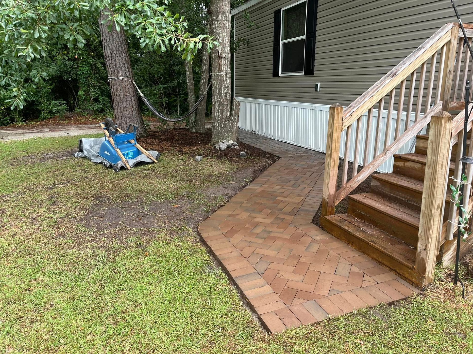 A wooden deck with stairs and a hammock in front of a mobile home.