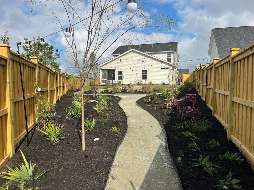 A wooden fence surrounds a path leading to a house.