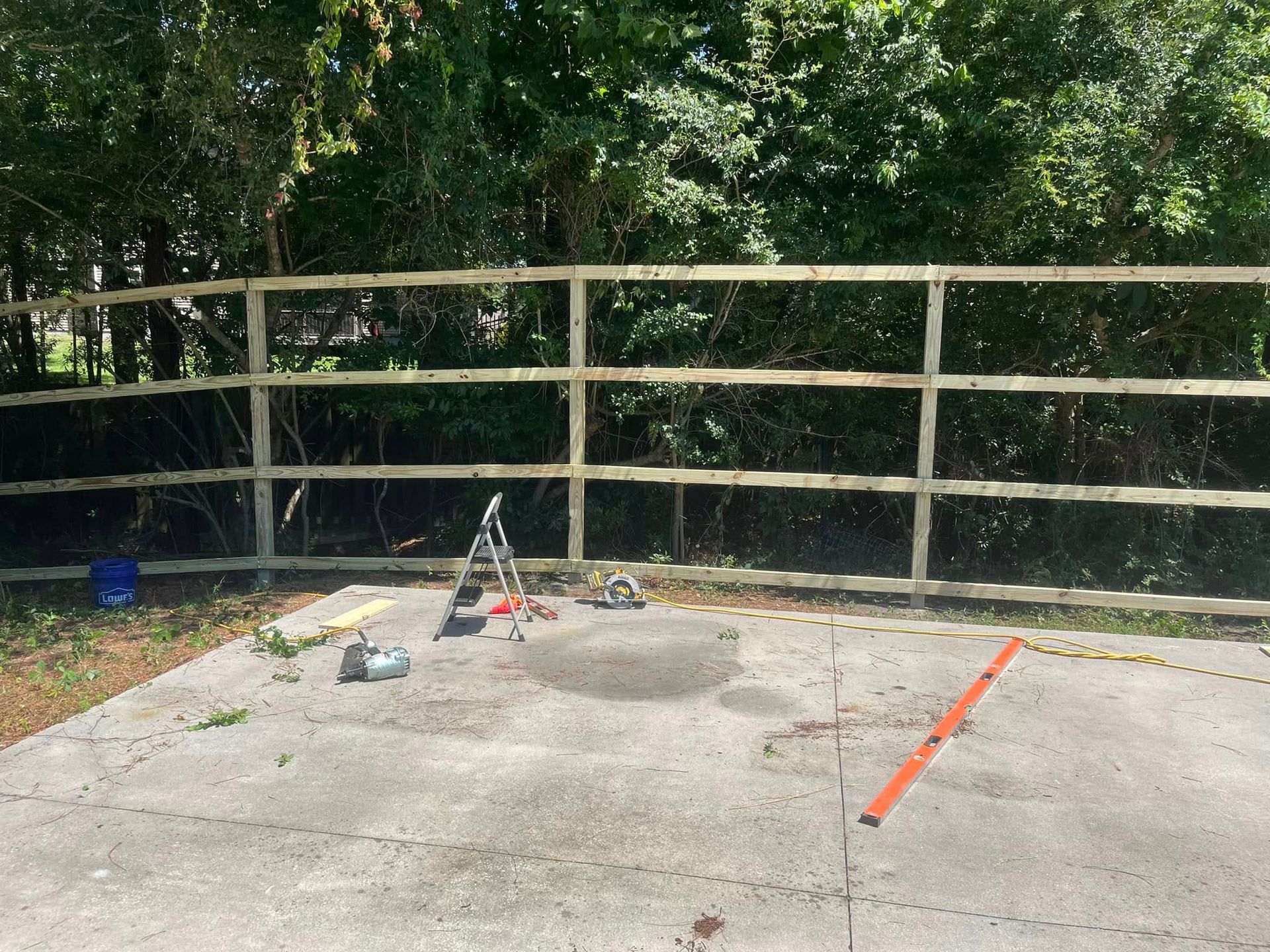 A wooden fence is being built in the backyard of a house.