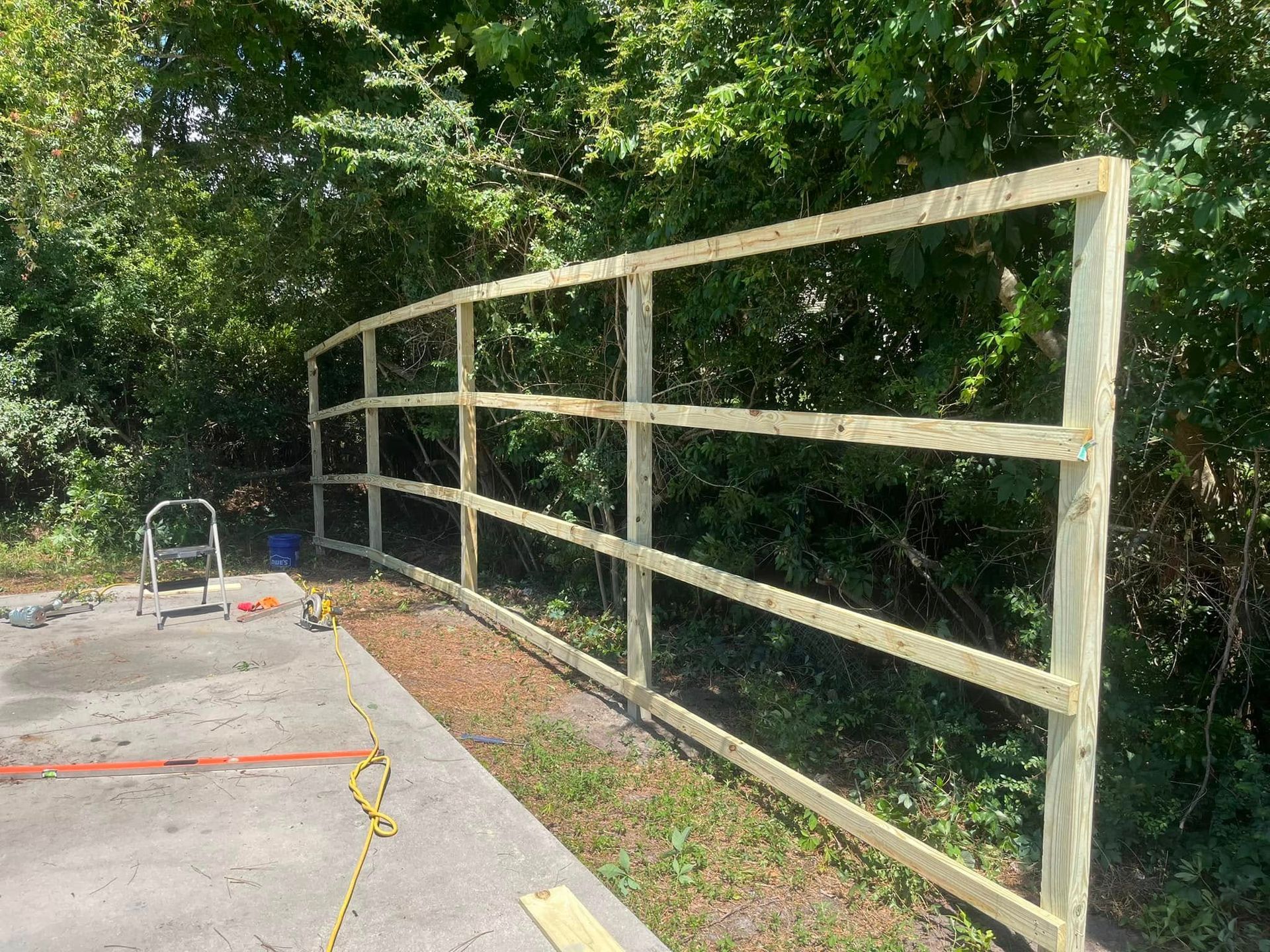 A wooden fence is being built next to a concrete driveway.