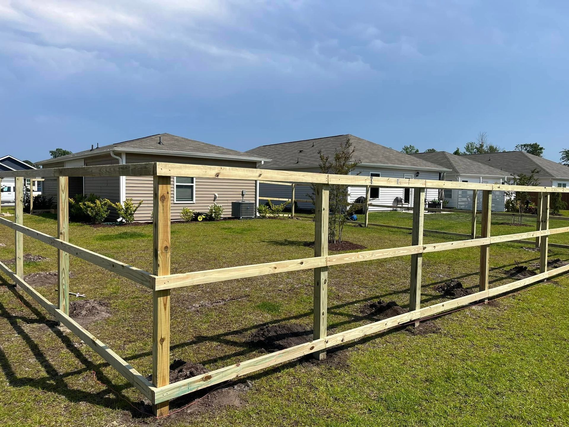 A wooden fence is being built in the backyard of a house.