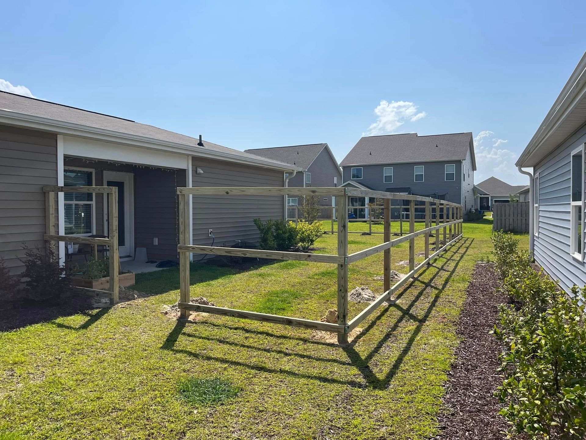 A wooden fence is being built in the backyard of a house.
