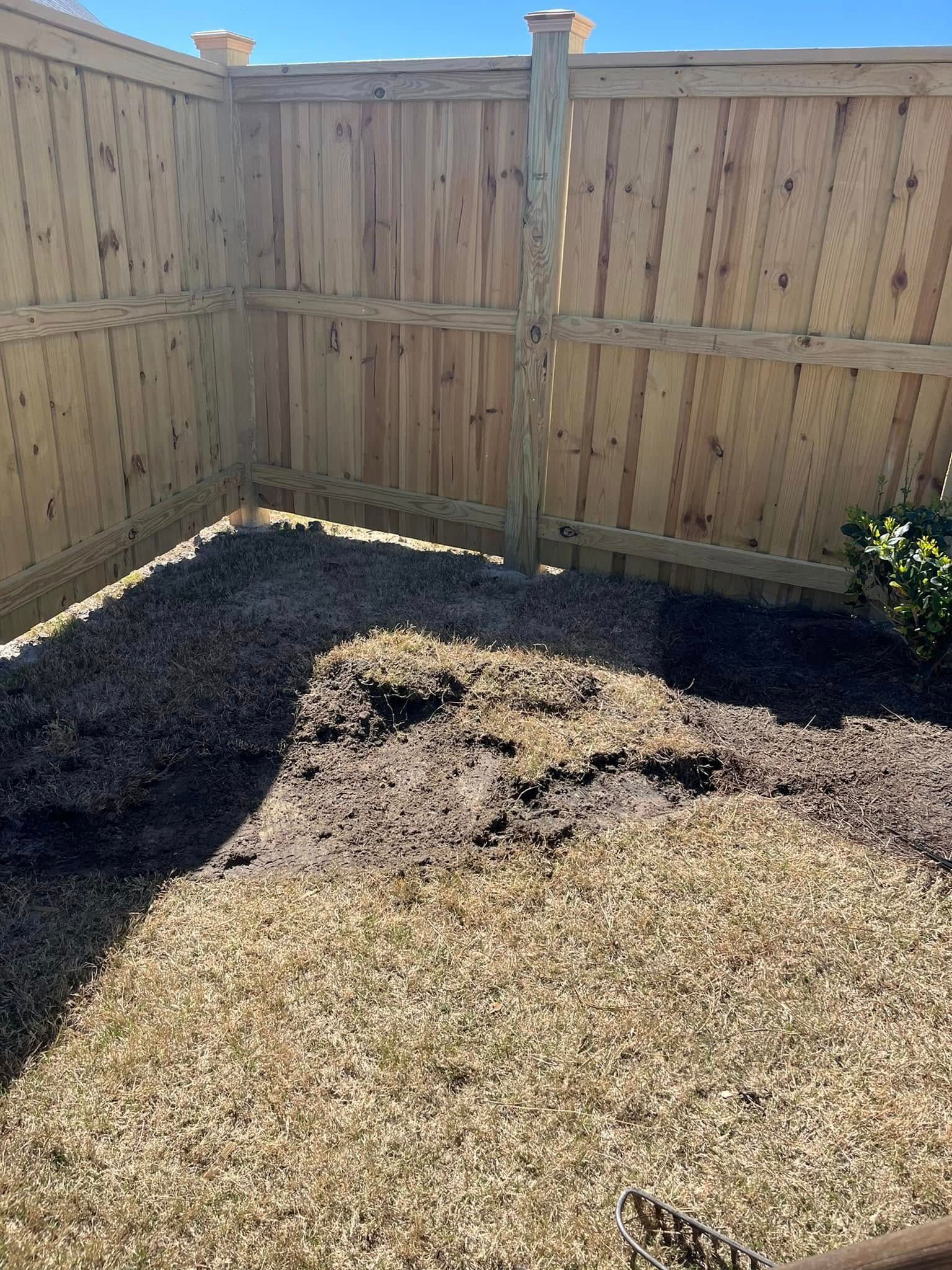 A wooden fence with a pile of dirt in front of it.