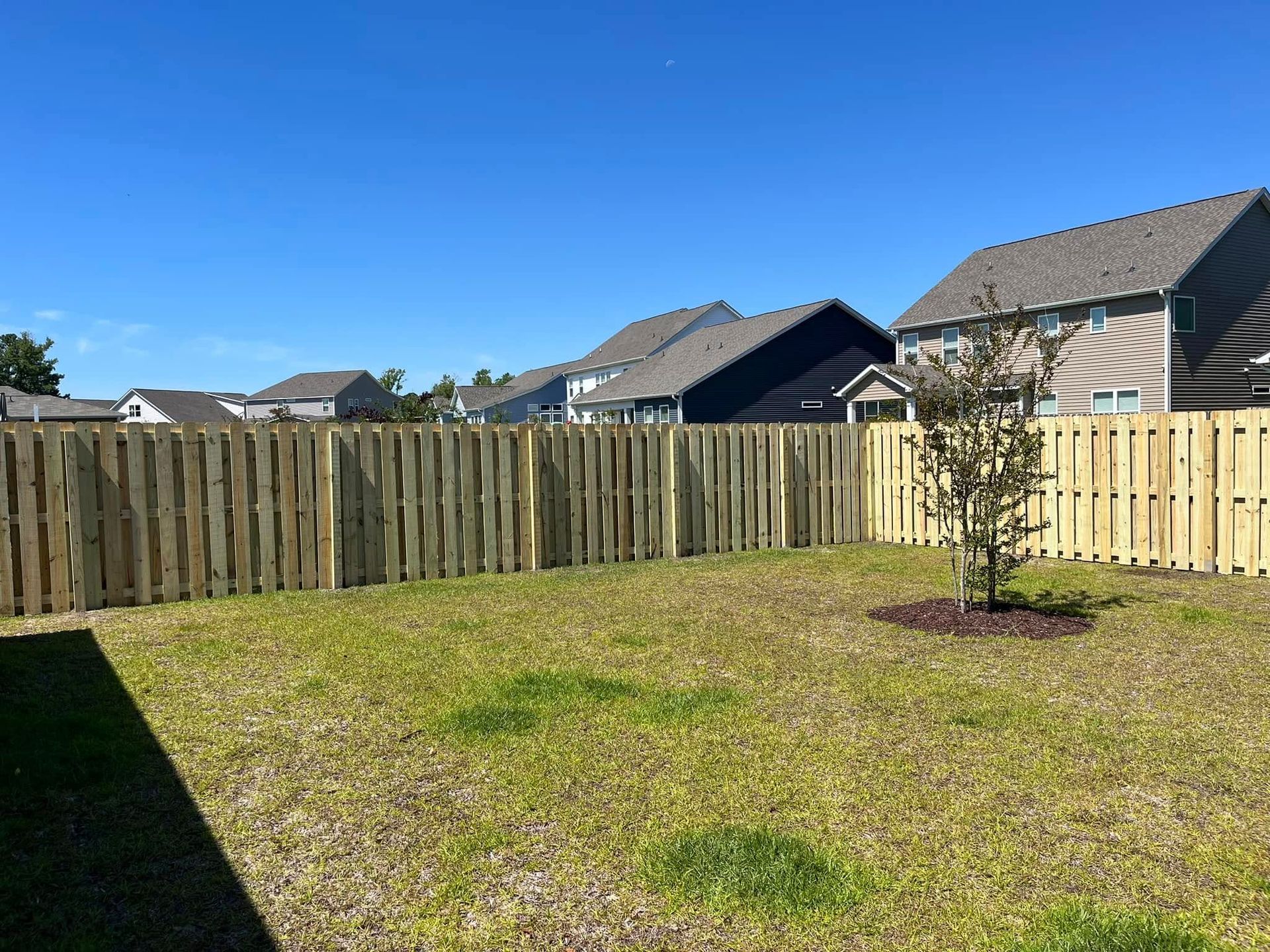 There is a wooden fence in the backyard of a house.