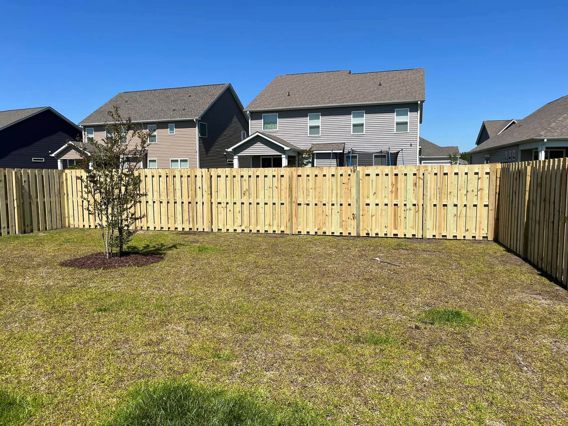 There is a wooden fence in the backyard of a house.