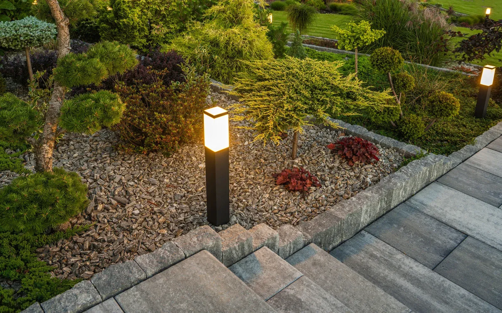 A garden with stairs and a lamp post in the middle of it.