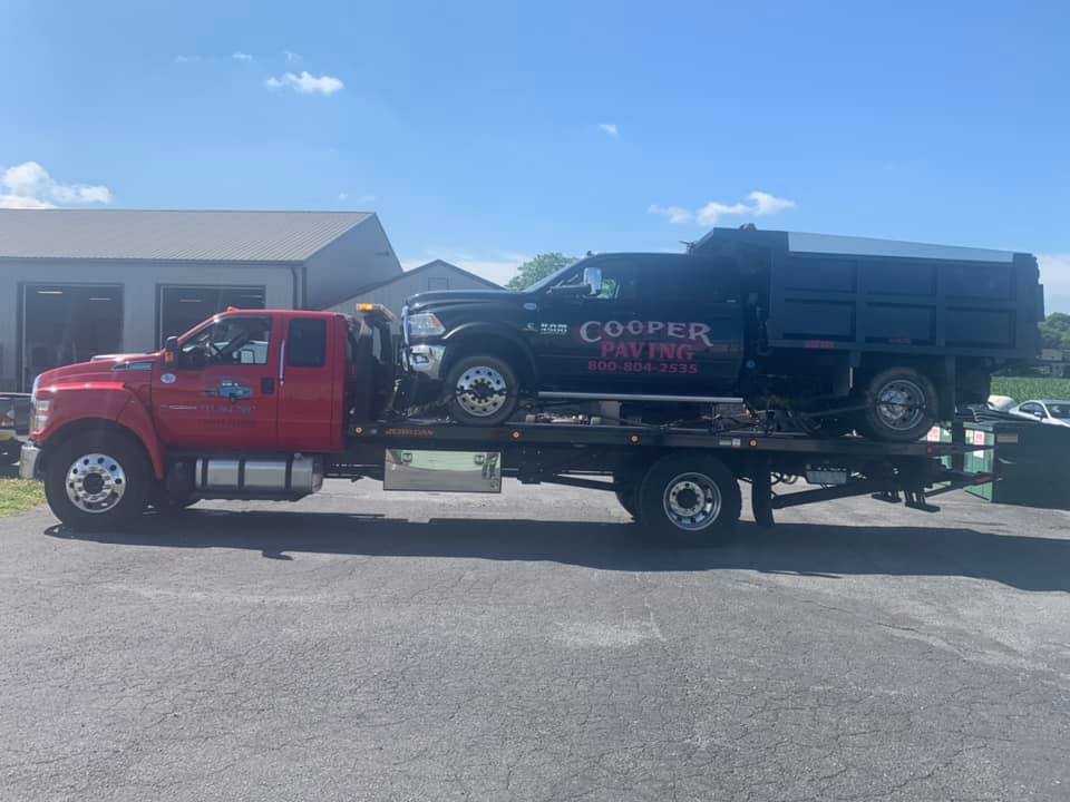 Tow truck carrying black service truck - Harrisburg, PA - Dingman’s Towing and Recovery LLC