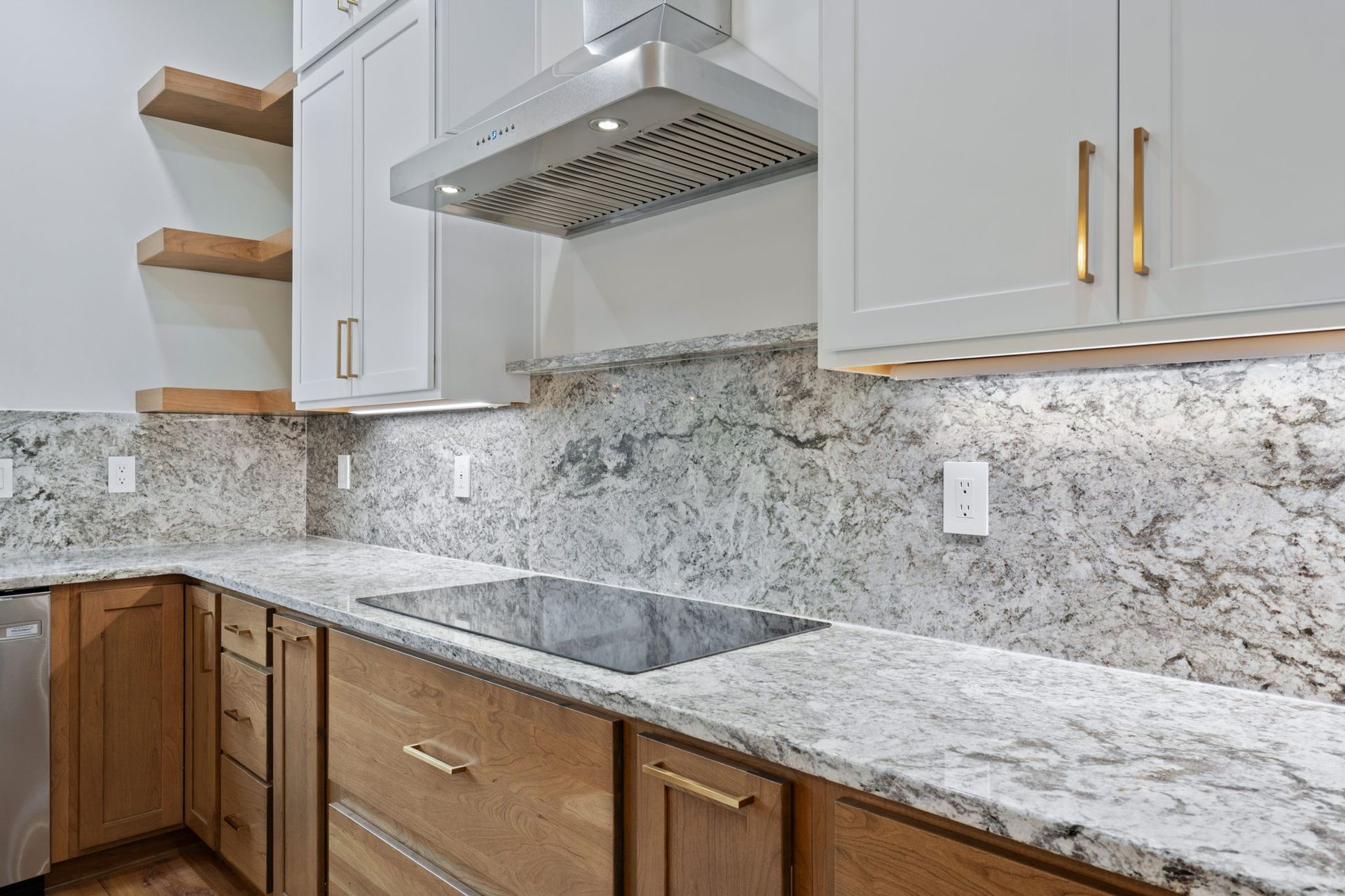 Close-up of modern kitchen with granite countertops, wood base cabinets, and sleek white uppers — custom home builder in Chattanooga.