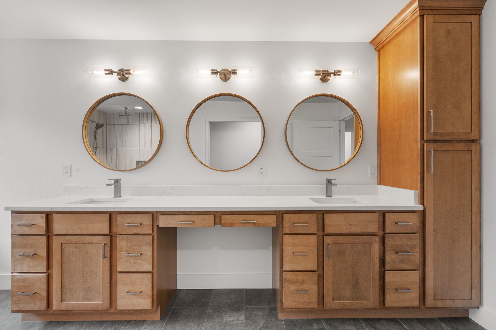 Custom bathroom with triple vanity, wood cabinetry, and round mirrors — built by custom home builder in Chattanooga.