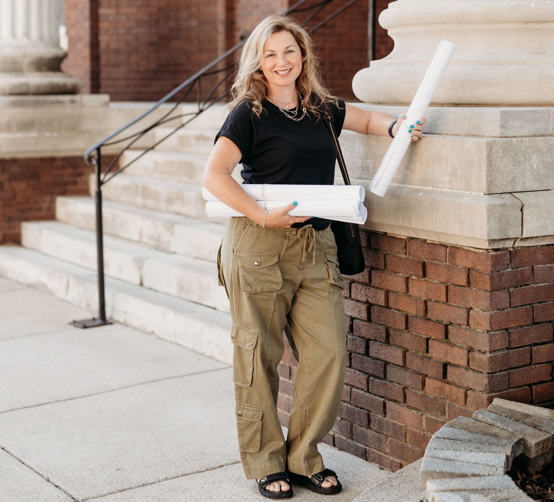 Collette Branham, owner of Tristar Custom Homes, smiling and holding blueprints on a job site in Chattanooga — custom home builder Chattanooga.