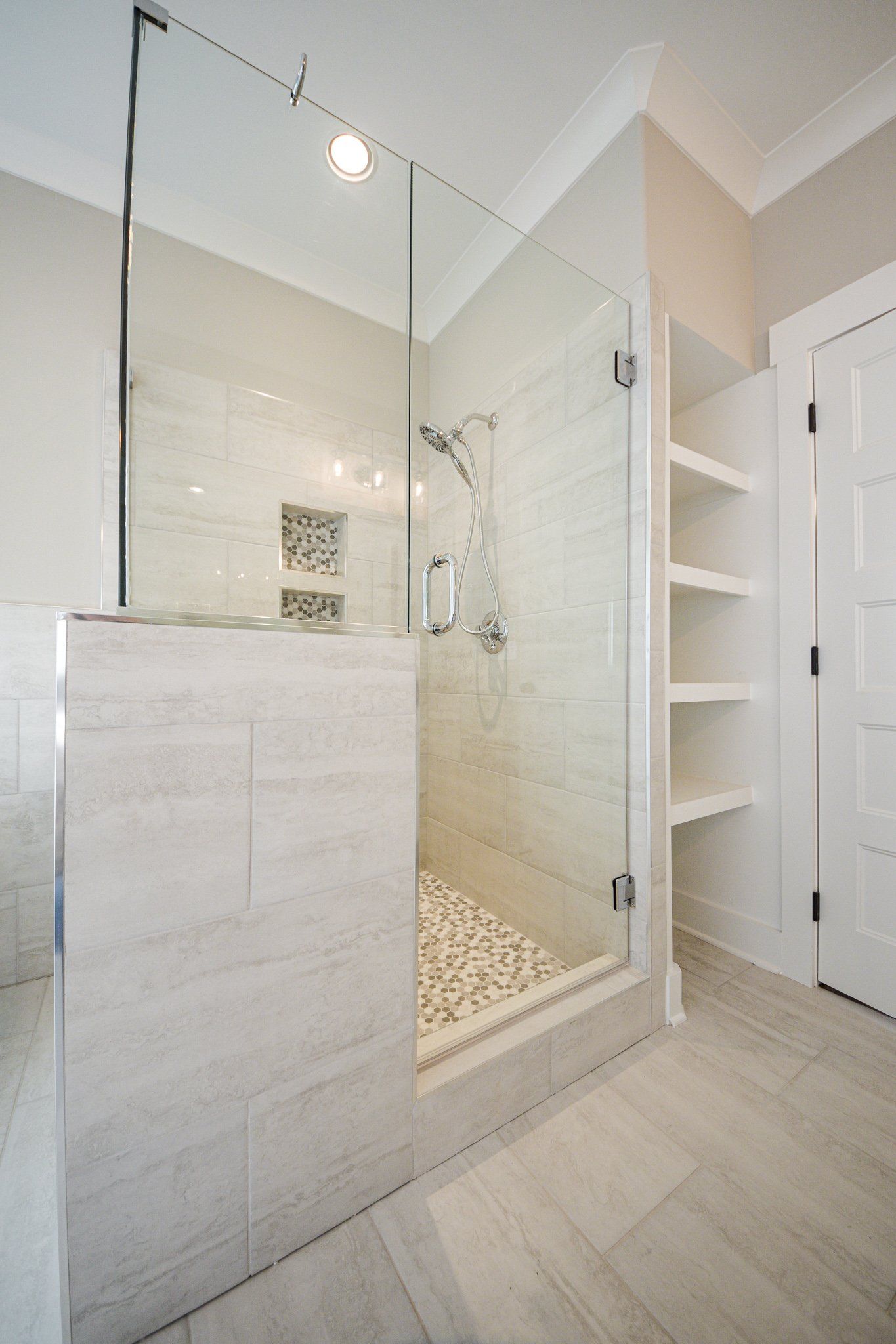 Custom tile walk-in shower with glass door, built-in shelving, and rainfall showerhead in modern Chattanooga bathroom remodel.