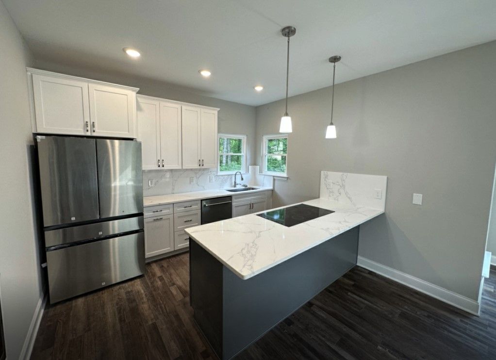 Custom home builder in Chattanooga presents a kitchen remodel featuring white cabinets, quartz countertops, and stainless steel appliances.