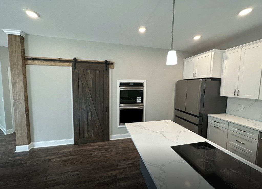 Remodeled kitchen with white cabinetry, quartz countertops, and sliding barn door — home remodeling Chattanooga.