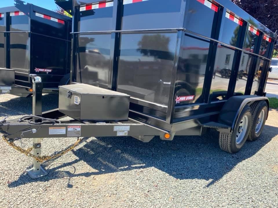 A dump trailer is parked in a gravel lot.