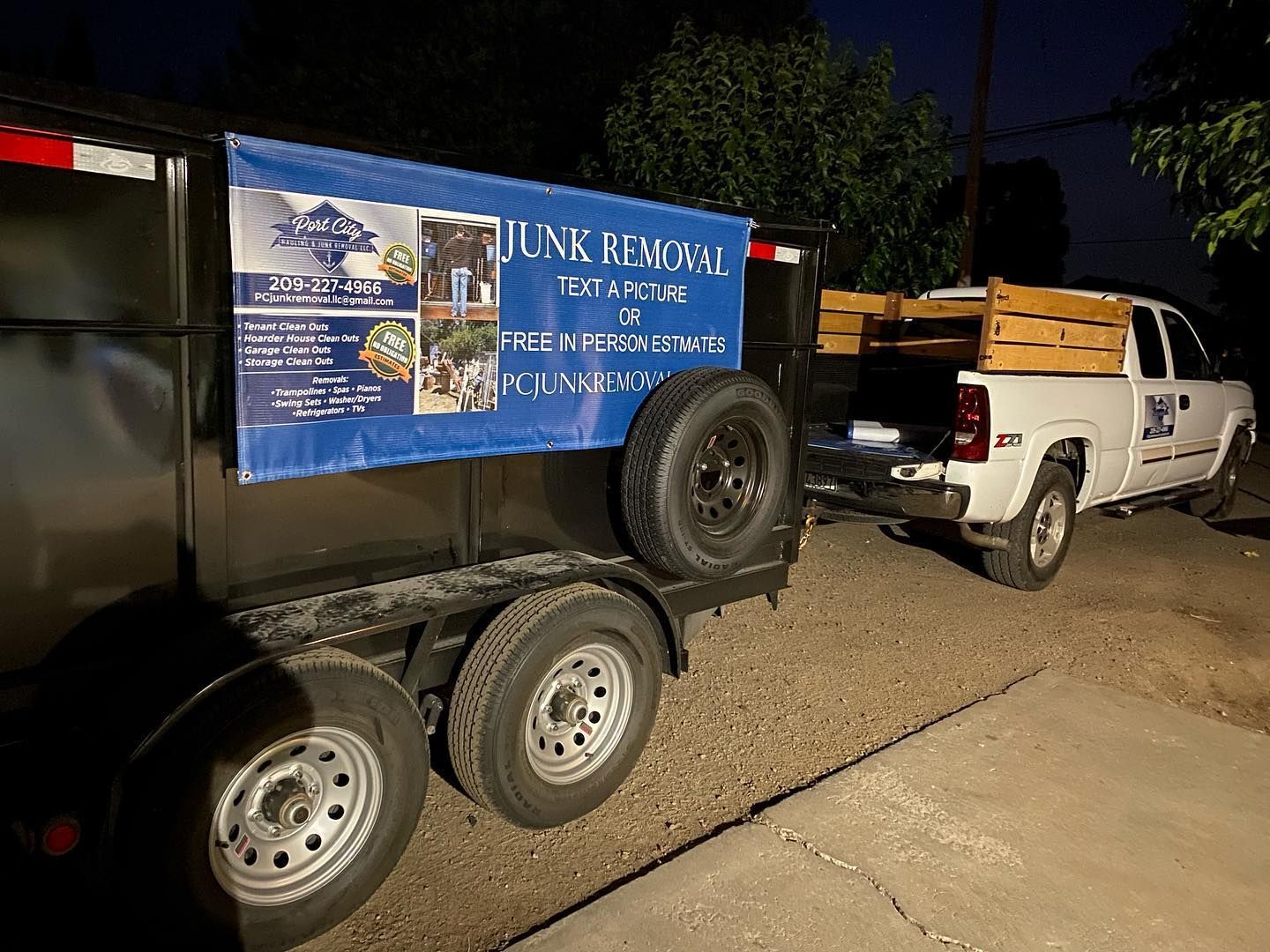 A white truck is pulling a trailer with a blue banner on it.