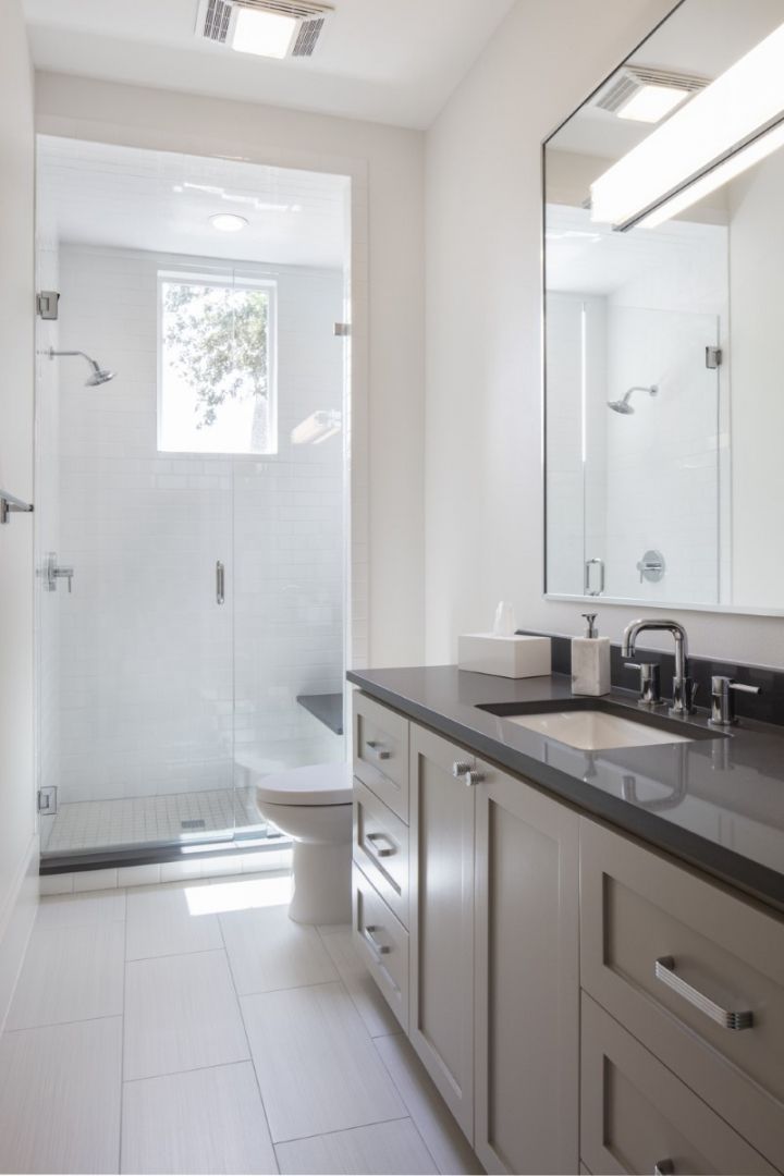 Modern bathroom with white walls, shower, vanity, and large mirror.