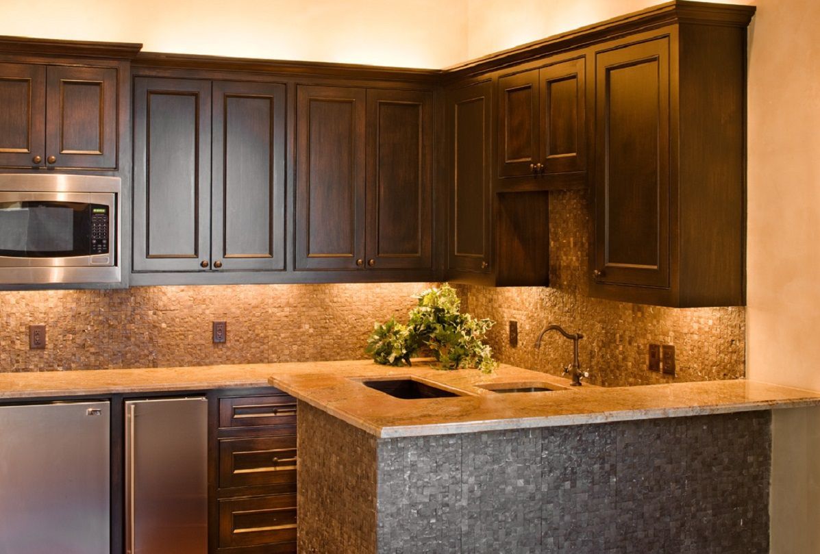 Dark wood kitchen cabinets with granite countertops, stainless steel appliances, and a backsplash.
