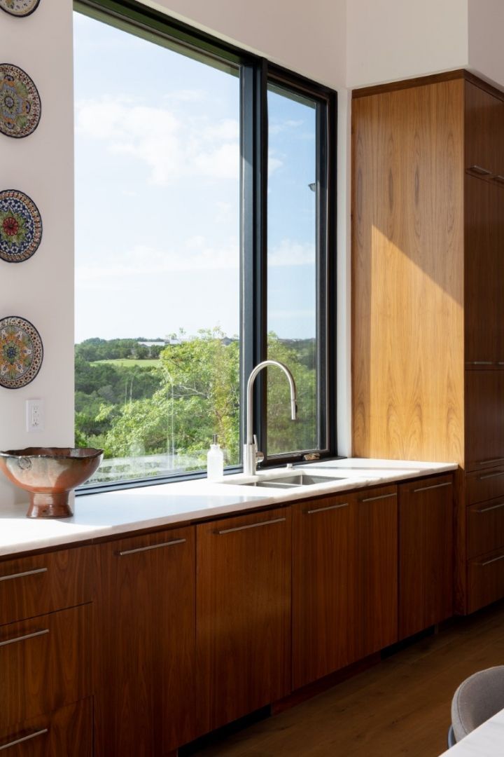 Kitchen with walnut cabinetry, white countertop, stainless sink, window with a view.