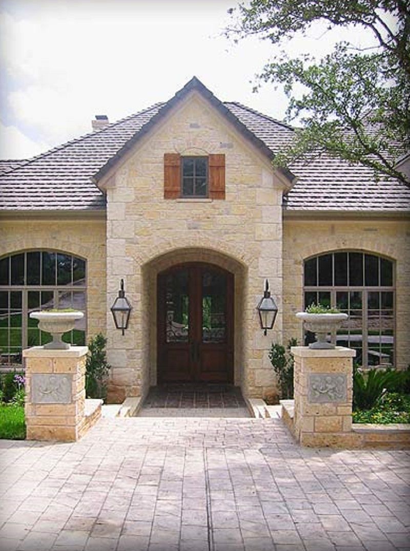 Stone facade entrance with arched door, windows, and brick pathway.