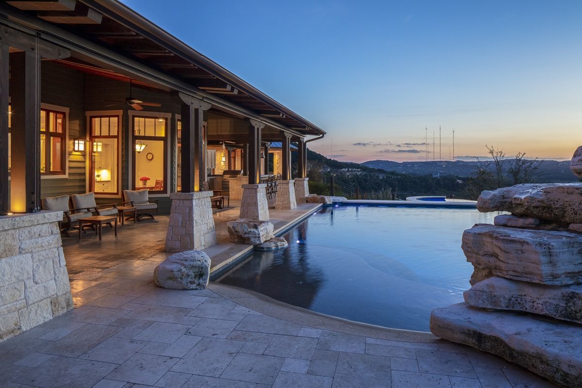 Patio with pool overlooking a landscape at dusk. Large rocks frame the pool's edge.
