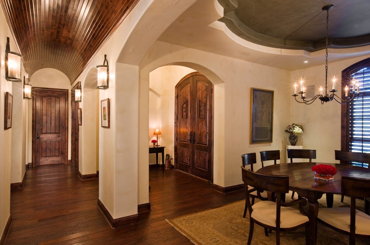 Hallway and dining room with wood floors, arched doorways, and chandelier.