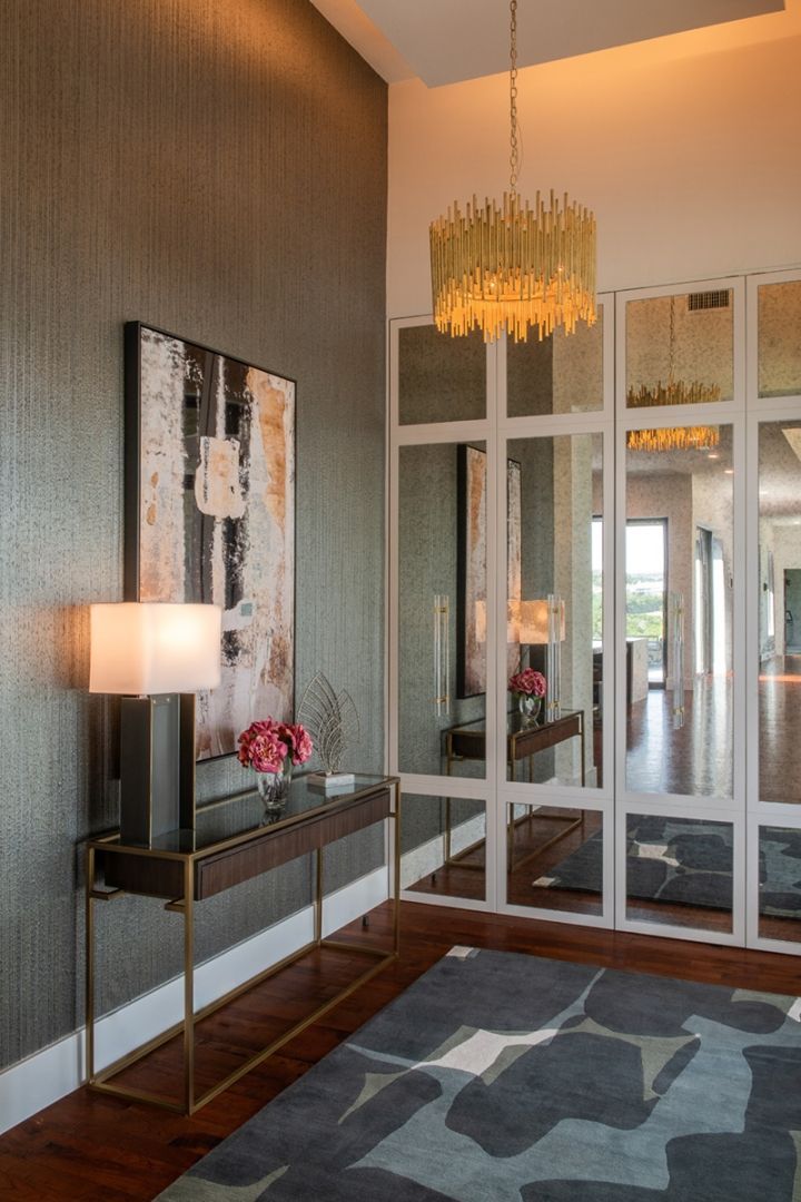 Entryway with abstract art, a table lamp, a gold chandelier, a console table, and a rug.