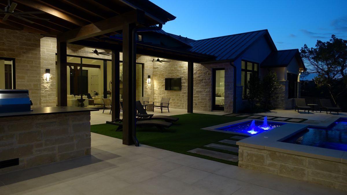 Night exterior of a modern home with illuminated pool and outdoor seating area.