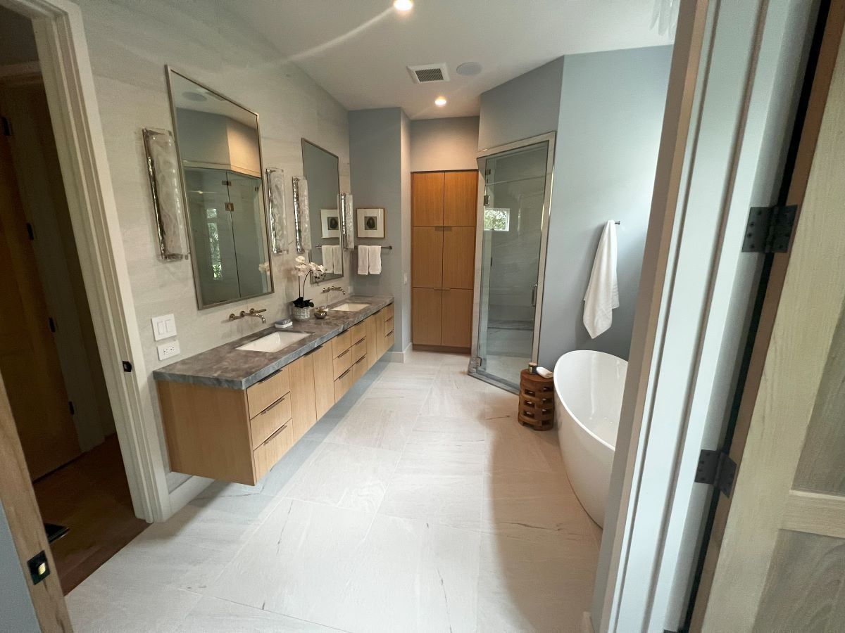 Modern bathroom with floating wood vanity, soaking tub, and glass shower.