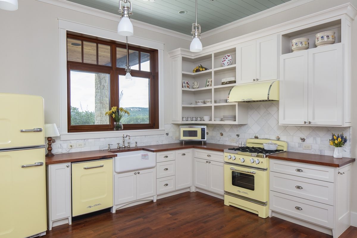 Yellow and white kitchen with retro appliances, dark wood counters, and a large window.