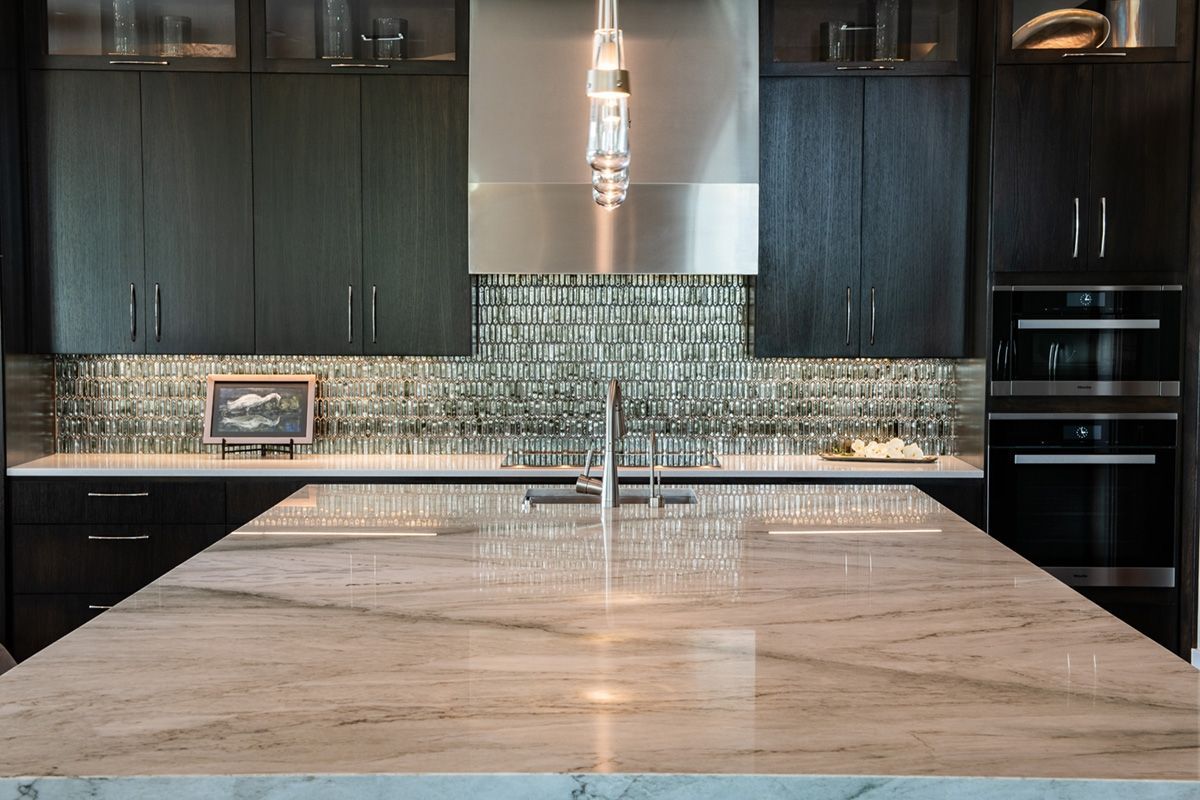 Modern kitchen with dark wood cabinets, light countertop, and stainless steel appliances.